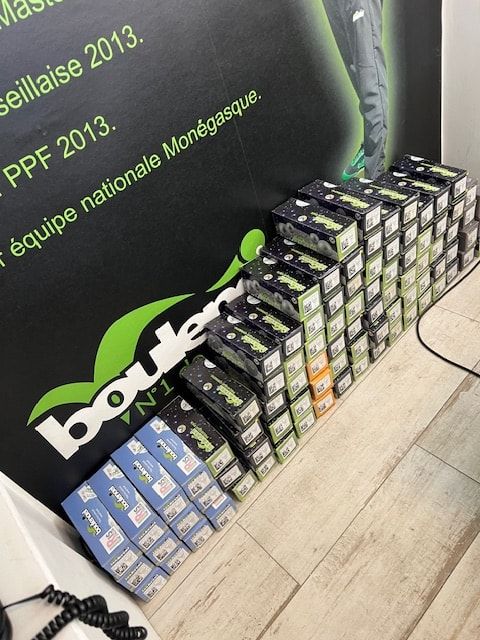 Piles de boîtes de boules Boulenciel au pied d'un mur de la boutique