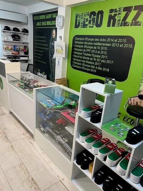 Vitrines de boules et rayon de chaussures devant le mur des palmarès de Diego Rizzi