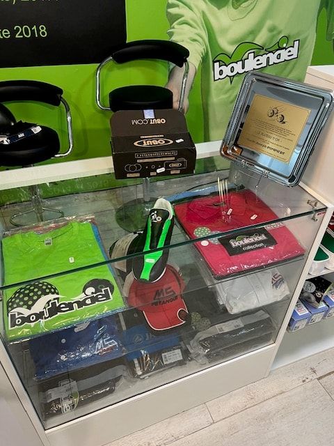 Vitrine avec polos Boulenciel, casquettes et une chaussure de pétanque
